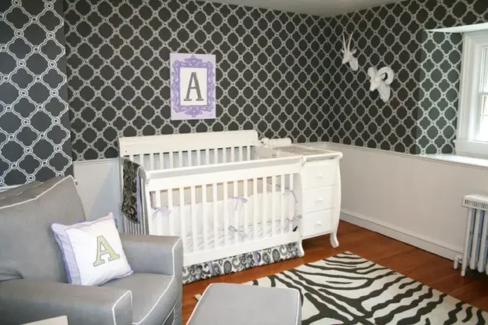 Gender-neutral nursery with white crib, geometric-patterned wall, and zebra-patterned rug, ideal for small nursery room ideas.