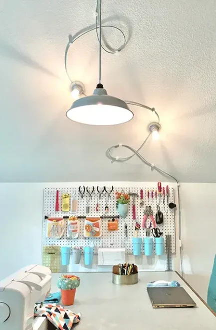 A neatly organized craft workspace with a sewing machine, tools on a pegboard, and various crafting supplies.