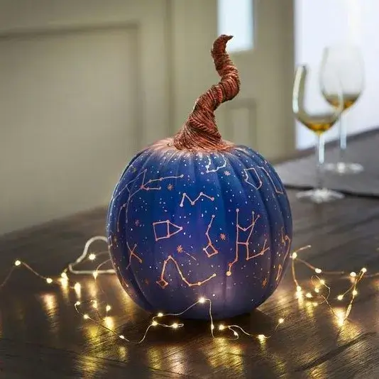 Blue pumpkin with constellations illuminated from within, adorned with string lights, perfect for easy and educational Halloween decorations with an astronomy theme.