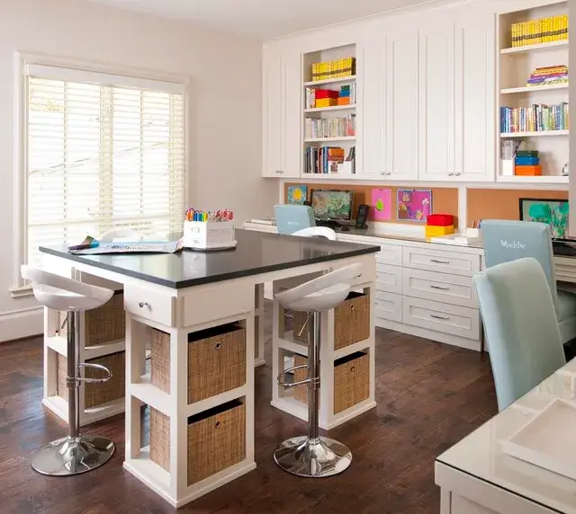 A well-organized home office with a central island, white cabinetry, and wicker basket storage.