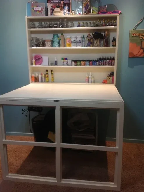 An organized small craft room with a pegboard wall and shelving, showcasing budget-friendly DIY storage ideas for art supplies.